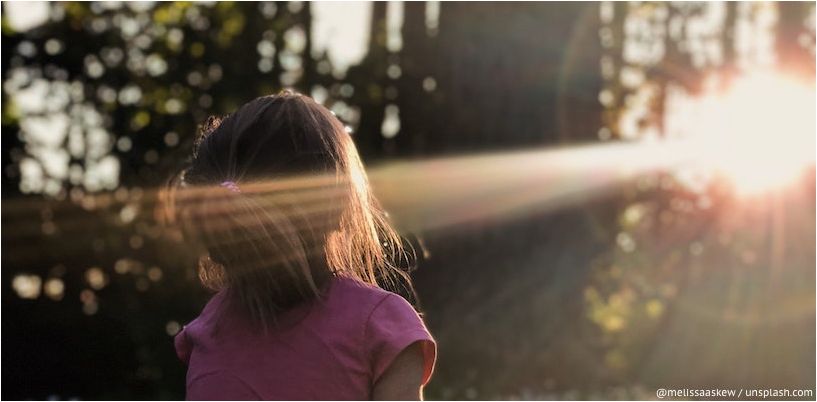 jenta ser på en solstråle i skogen