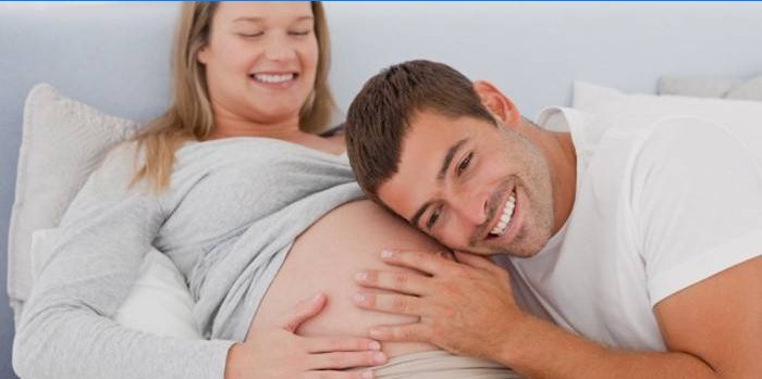 En mann lytter til en baby som beveger seg i magen til moren