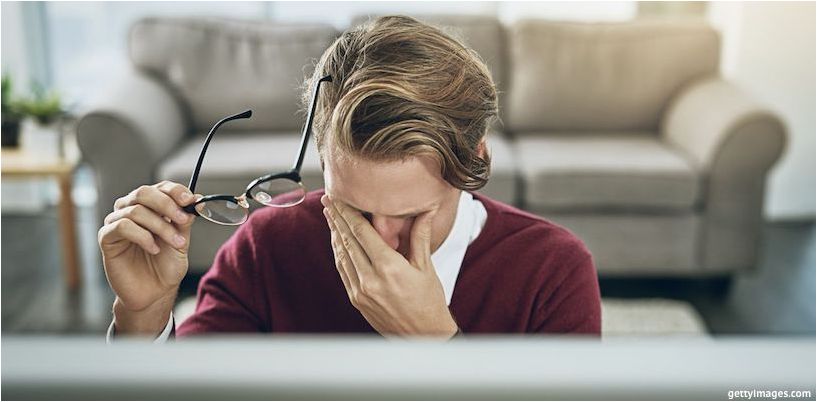 en mann gnir øynene foran en datamaskin