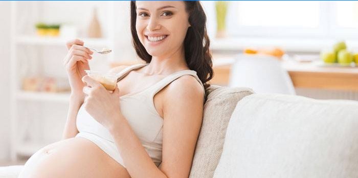 Gravid jente som sitter på en sofa