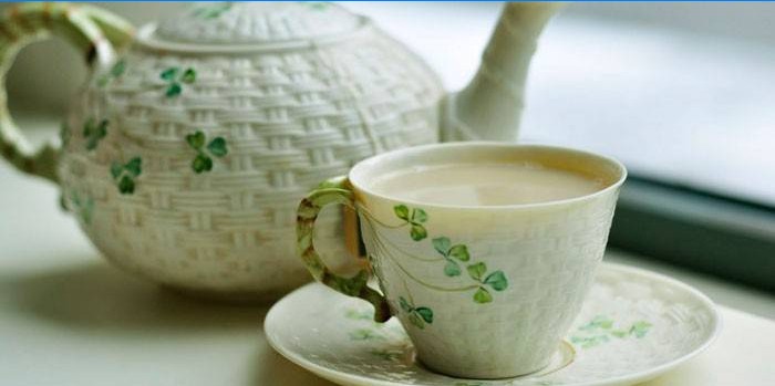 Grønn te med melk i en kopp og tekanne