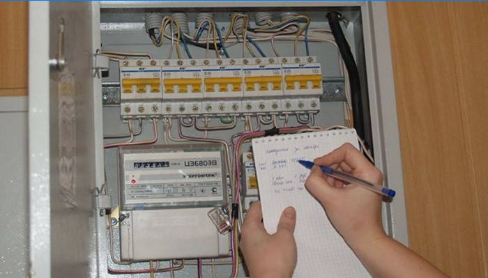 En mann registrerer avlesningene til en elektrisk måler