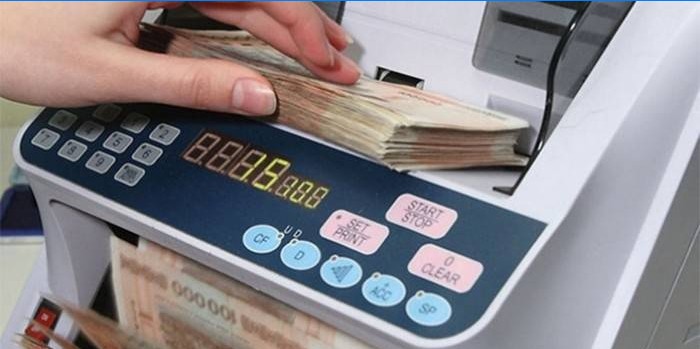 Kvinne teller penger med en regningsmaskin
