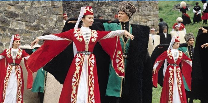 Kvinner og menn i tsjetsjenske kostymer dans