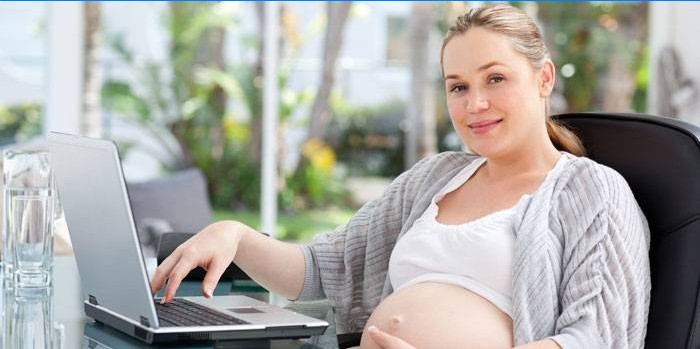Gravid jente på en bærbar datamaskin