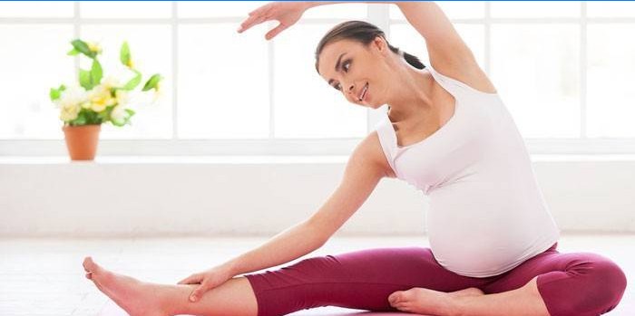 Gravid jente gjør øvelser hjemme.