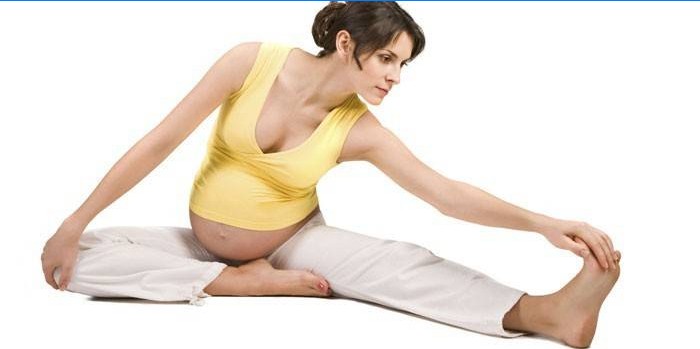 Gravid jente som gjør strekkeøvelser