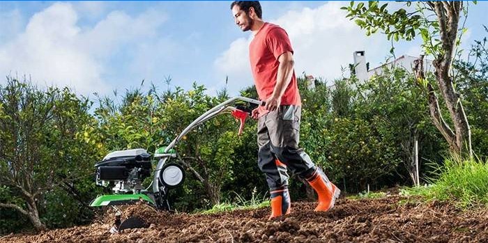 En mann graver en hage ved hjelp av en walk-bak traktor