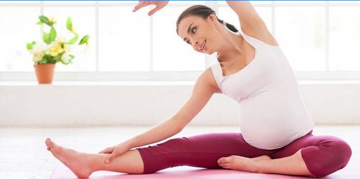 Gravid jente som driver med pilates hjemme