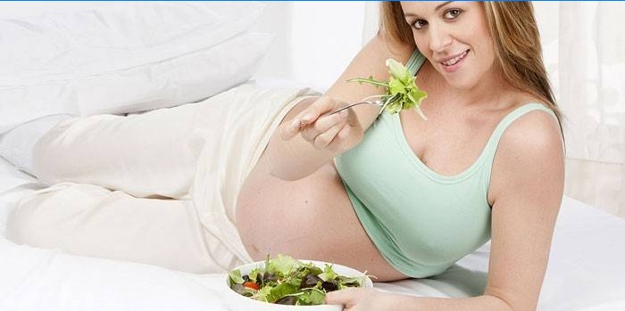 Gravid jente som spiser salat