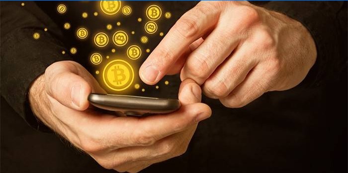 Mann med smarttelefon i hendene og bitcoin-ikoner.