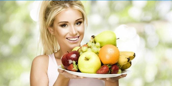 Jente holder en tallerken med frukt og bær.