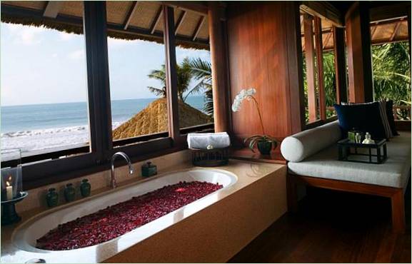 Bad med rosenblad ved vinduet med utsikt over havet